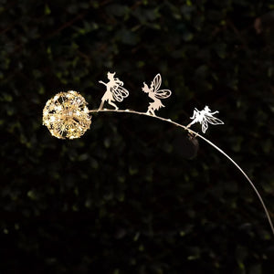 Solar dandelion fairy stake light glowing in garden at night