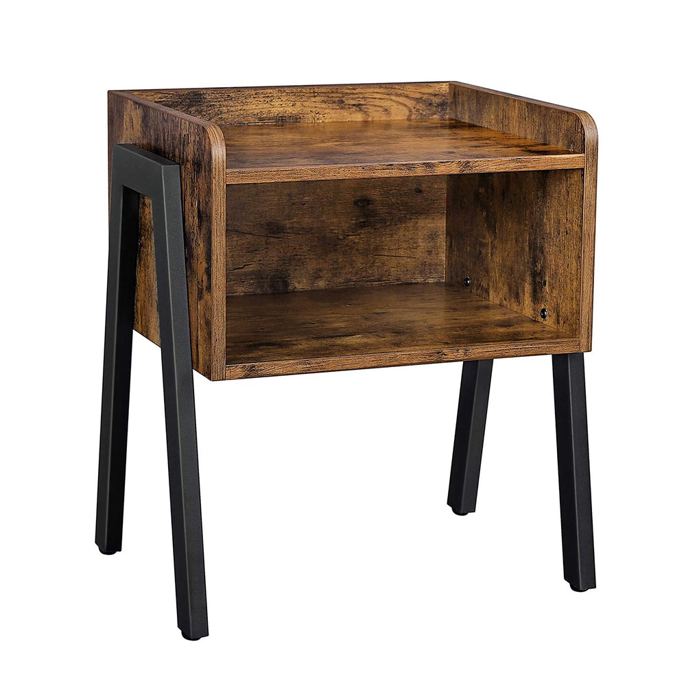A rustic wooden end table with black metal legs, styled in a cozy living room next to a beige sofa. The table features a warm medium-brown wood finish with visible grain, a single open shelf holding a book and decorative stone, and a small white ceramic vase with greenery on top.