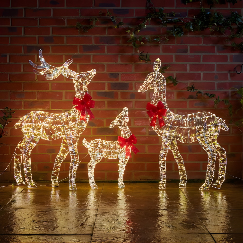 Decorative LED reindeer family with red bows against a brick wall.