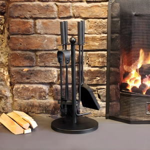 Black fireplace tool set with firewood in front of a lit fireplace.