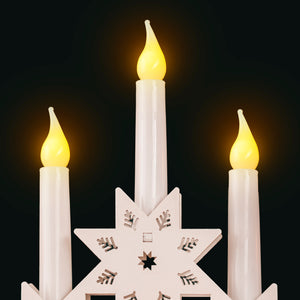 Star-shaped candle holder with three lit candles against a black background