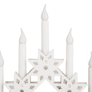 Decorative candle holder with star design and white candles on a white background
