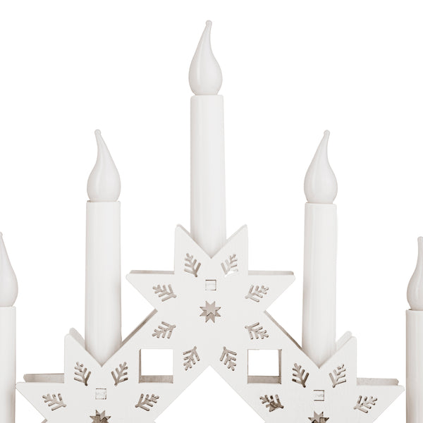 Decorative candle holder with star design and white candles on a white background