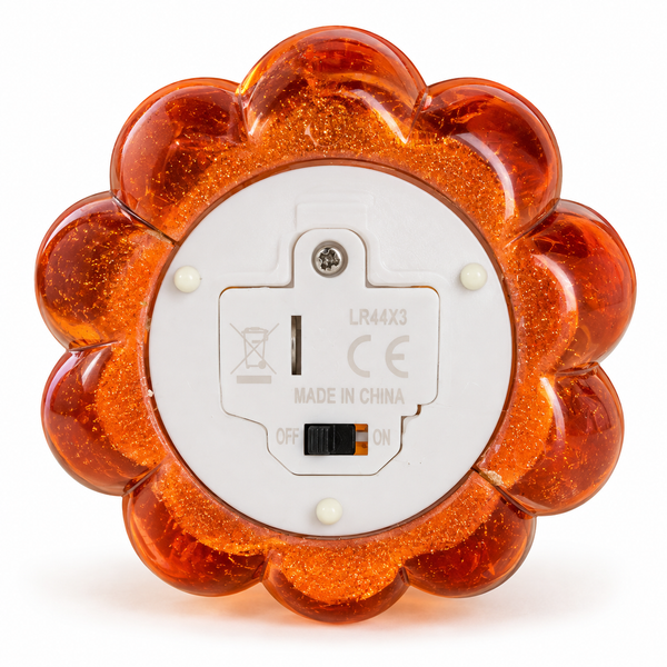 The back of a flower-shaped amber LED night light with a white circular base, featuring a power switch and regulatory markings.