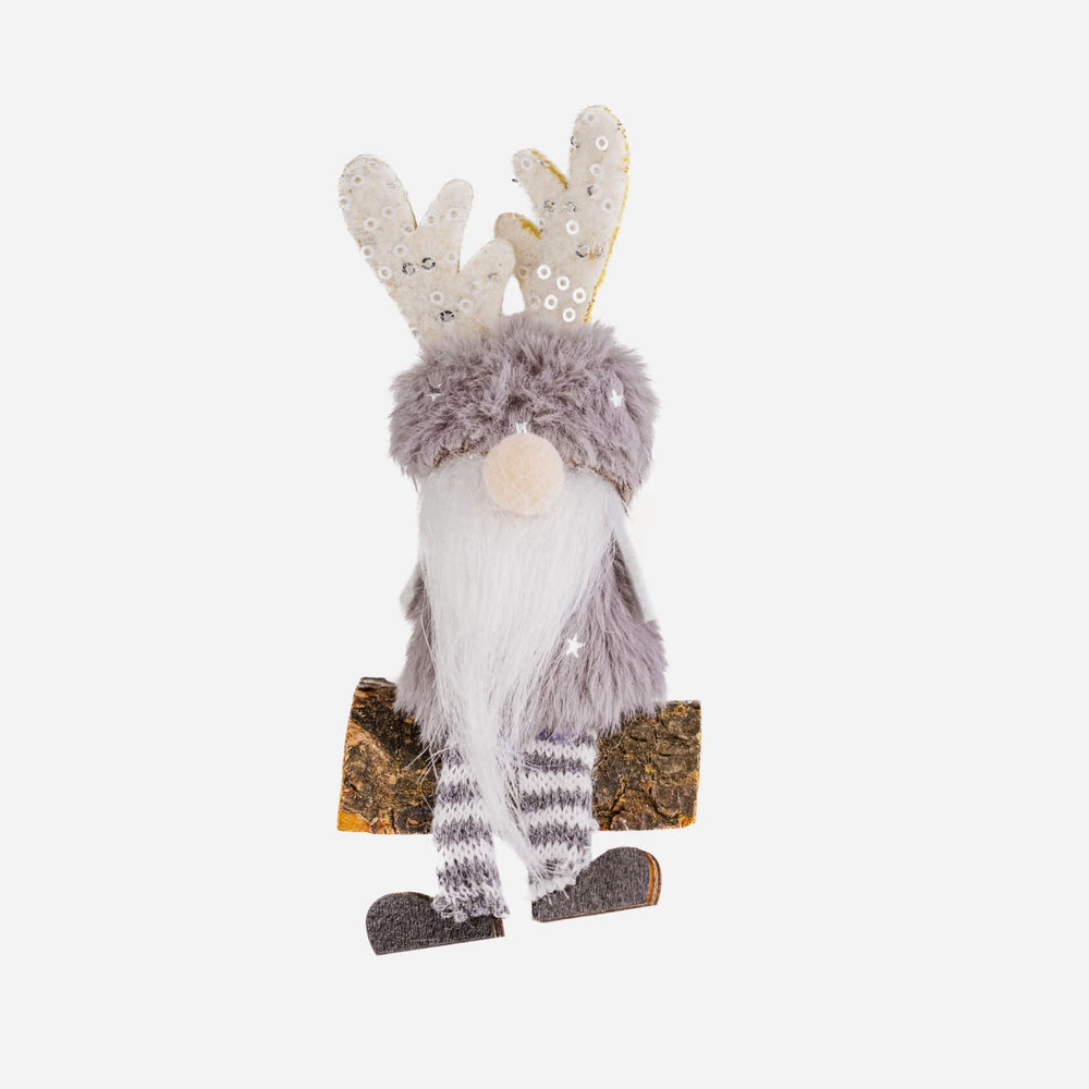 Decorative gnome with reindeer antlers sitting on a branch against a green background