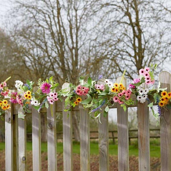 Colourful artificial flower garland hanging on garden fence