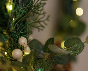 Sage leaves and white berries surrounding a decorative hoop
