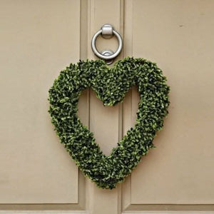 Boxwood heart wreath hanging on an outdoor garden door