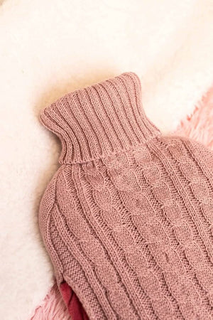 Close-up of a pink knitted sweater with cable pattern on a light background