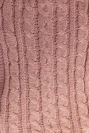 Close-up of a pink knitted fabric with cable pattern