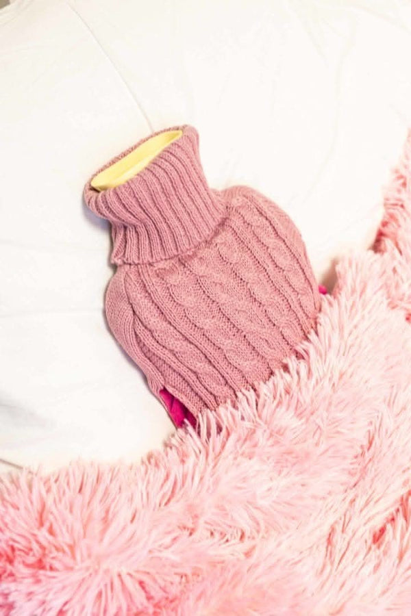 Pink knitted dog sweater on a fluffy pink blanket
