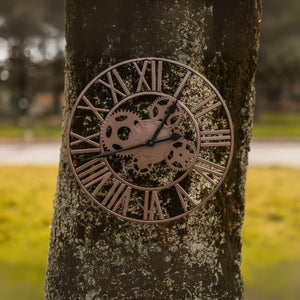 Decorative cog wall clock displayed in a garden