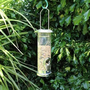 Bird feeder hanging from a tree branch with green leaves in the background
