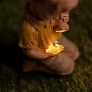 Resin boy statue standing beside a decorative duck