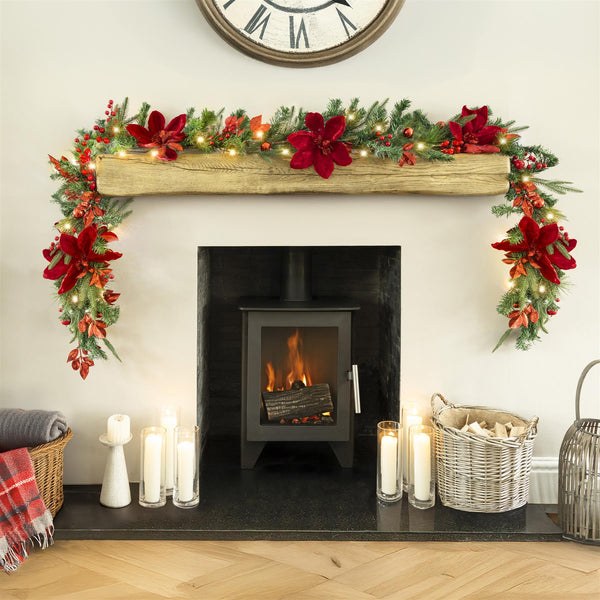 Decorated fireplace with Christmas garland, candles, and a clock on the wall.