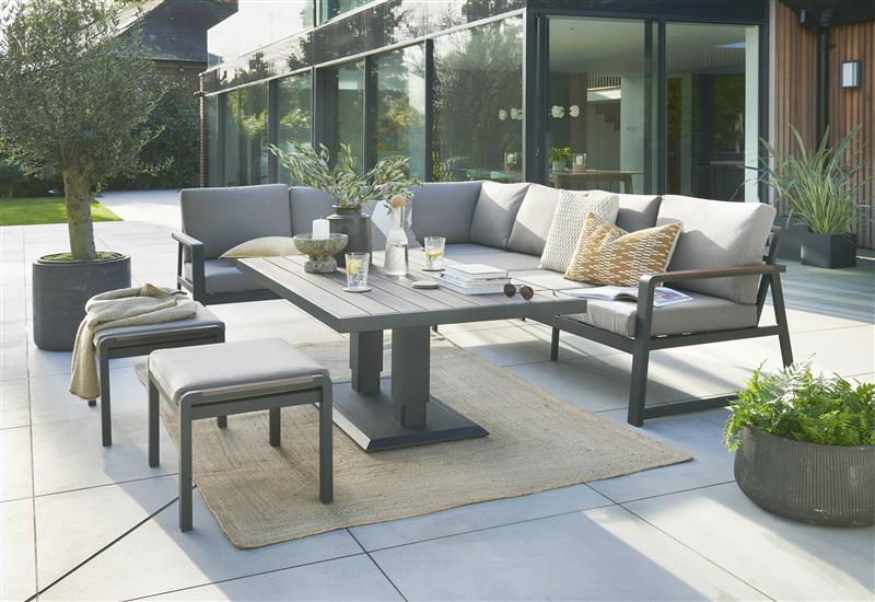 Outdoor patio set with gray sofa, table, and chairs on a tiled patio.