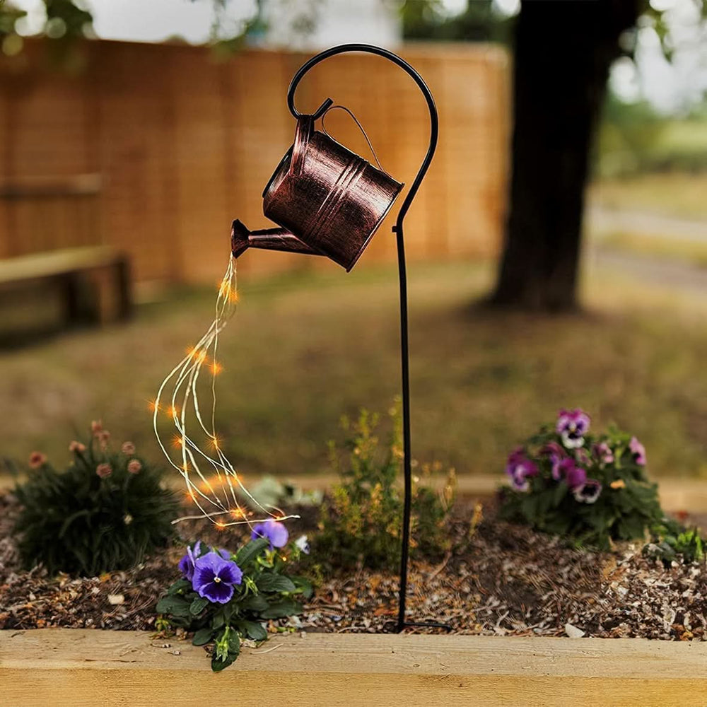 Cascading solar watering can light displayed above flowers