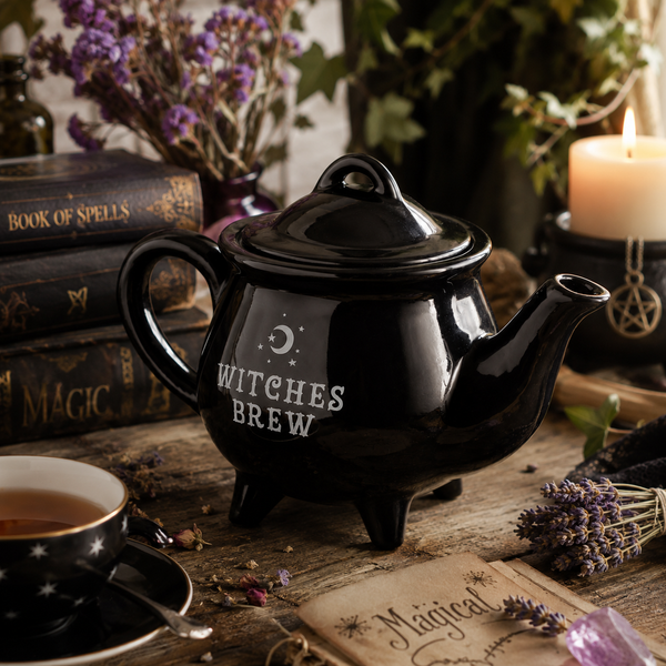 Cauldron shaped teapot arranged with witchy kitchen accessories