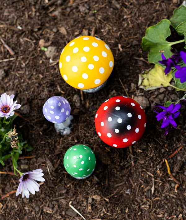 Colourful mushroom decorations displayed in garden flowerbed