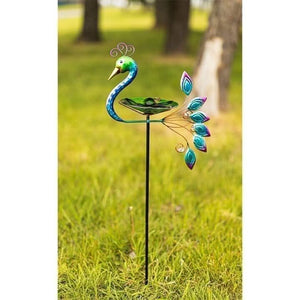 Staked peacock bird bath positioned on garden lawn