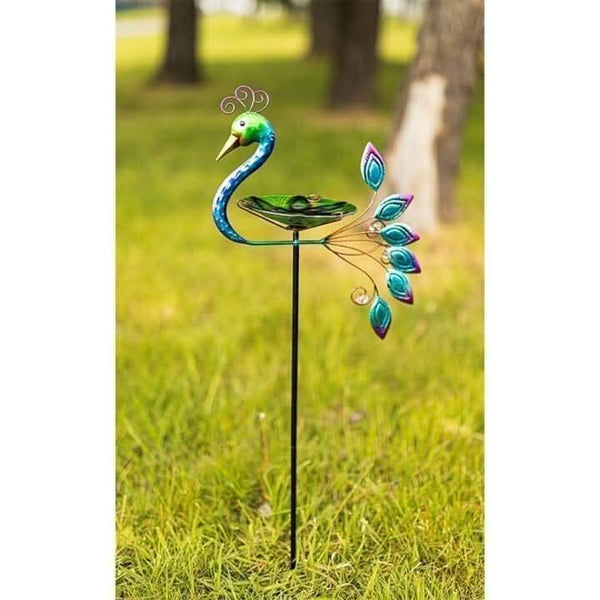 Staked peacock bird bath positioned on garden lawn