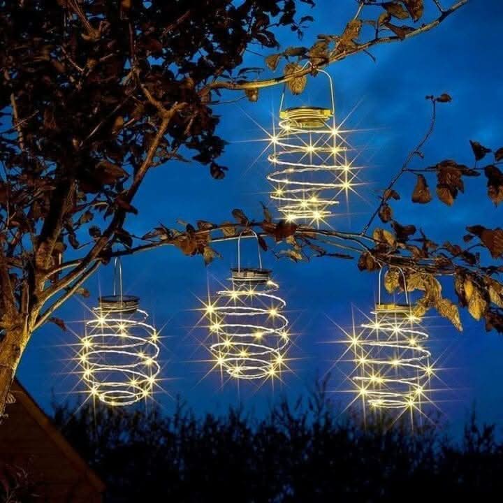 Four copper spiral lights hanging in an outdoor display