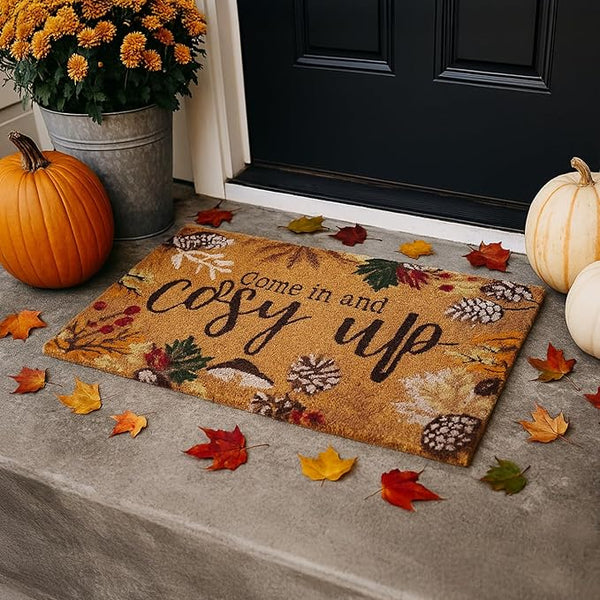Decorative doormat with autumn theme and pumpkins on a doorstep
