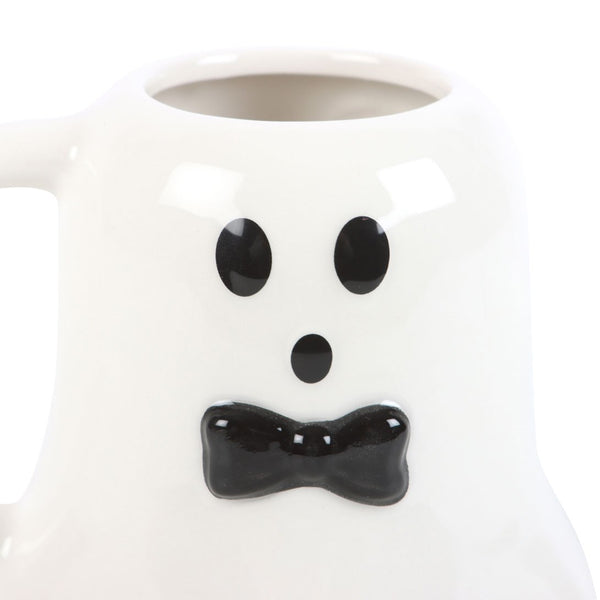 White mug with ghost face design featuring black eyes and bow tie on a white background