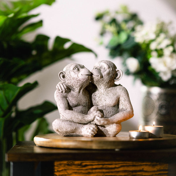 Kissing monkey sculpture positioned beside plants