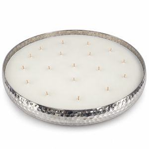 A large round multi-wick candle in a hammered silver metal tray, filled with white wax and featuring multiple small wooden wicks arranged in a grid pattern, set against a plain white background.