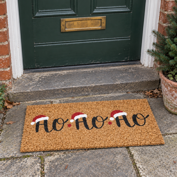 Ho Ho Ho Christmas coir doormat on a grey stone doorstep outside a dark green front door.
