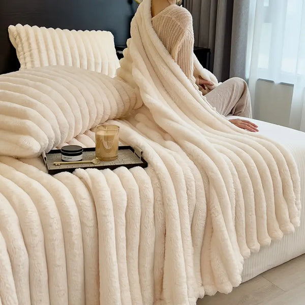 Faux fur throw blanket on a bed and draped over person.