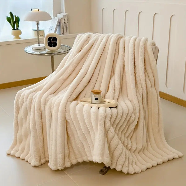 Faux fur throw blanket on a bed and draped over chair.