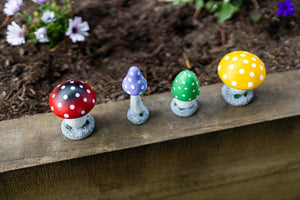Four hand-painted garden mushrooms shown together