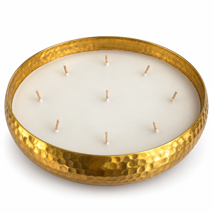 A hammered gold metal candle holder with multiple wicks, filled with white wax,placed on a white background 