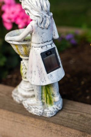 Solar powered fairy ornament beside flower bed