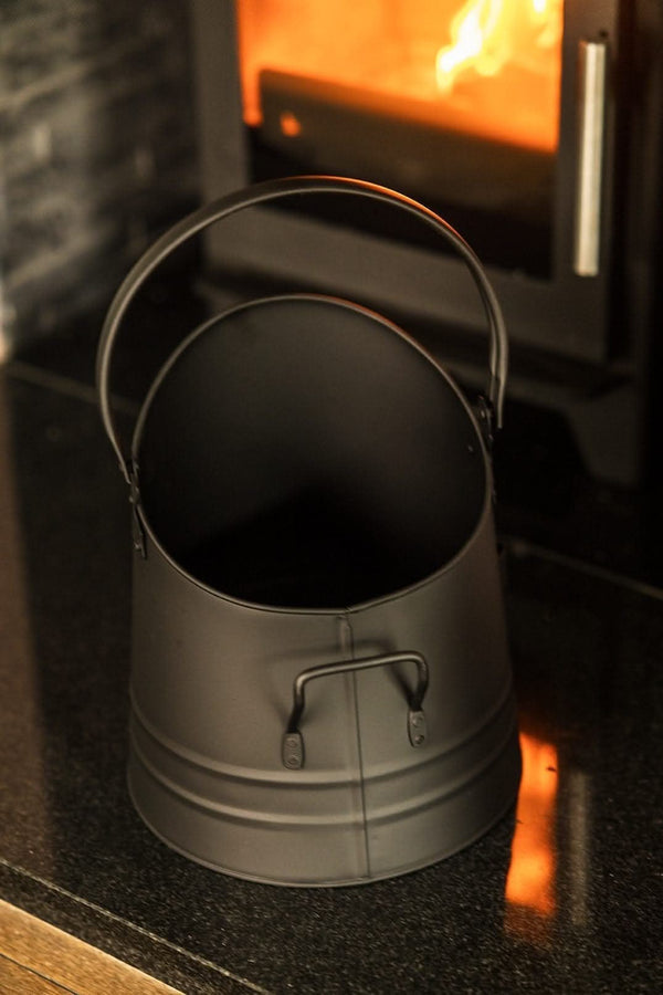 Black coal bucket displayed beside fireplace