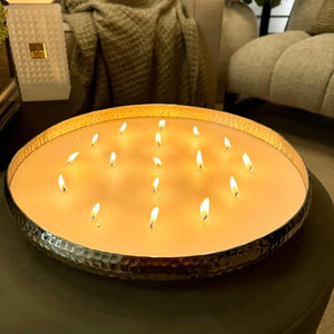 Large round candle with multiple small candles inside on a dark surface