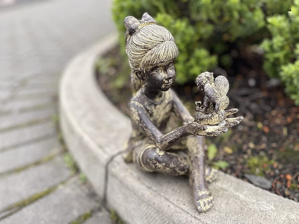 Girl holding fairy decoration positioned in a rockery