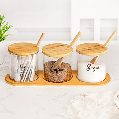 Three glass kitchen jars displayed on a wooden tray