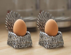 Two eggs in decorative metal holders on a wooden surface