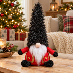 A festive Christmas gnome decoration sitting on a wooden table in a cozy living room setting, with a lit Christmas tree and holiday decorations in the background.