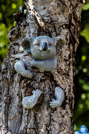 Cute koala ornament hugging a garden tree
