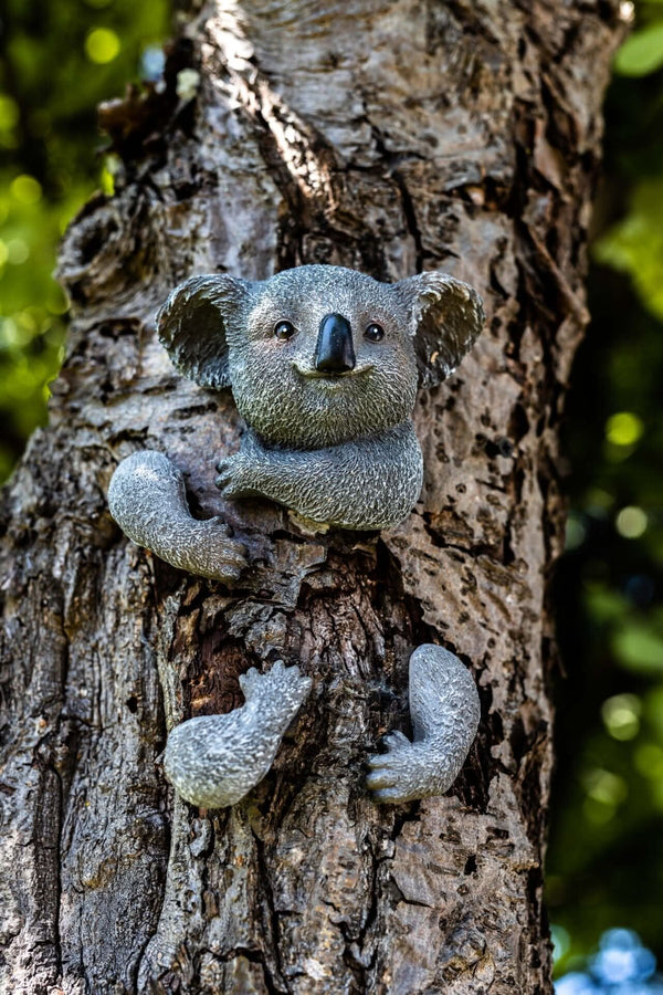 Cute koala ornament hugging a garden tree