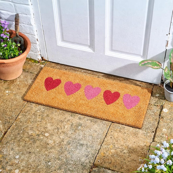 Natural coir doormat with decorative love heart design.