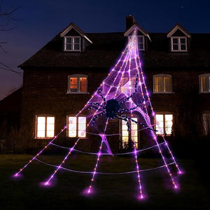 Halloween spider web light decoration in front of a house at night