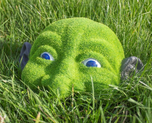 Decorative peeking head positioned on hedge