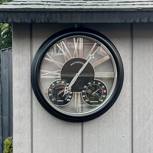 Black garden clock with Roman numeral face