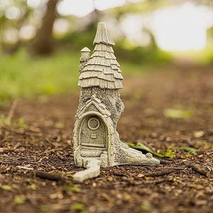 Decorative fairy house positioned beside a garden pathway