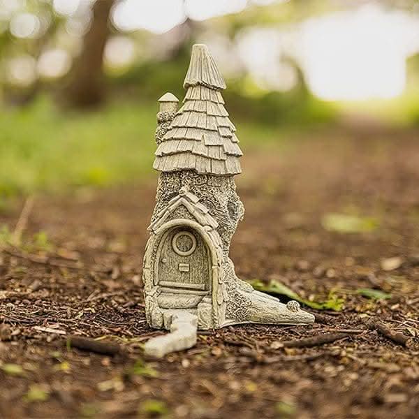 Decorative fairy house positioned beside a garden pathway